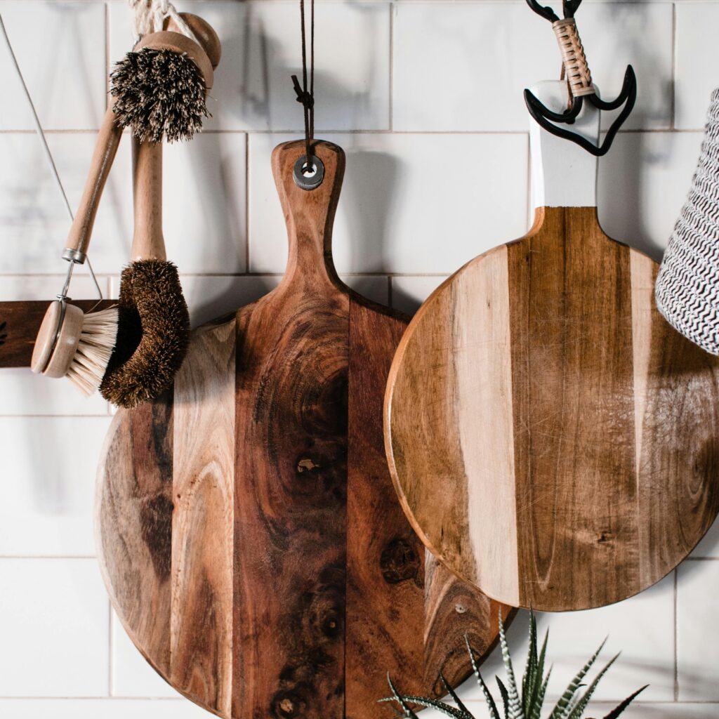 Charming wooden kitchenwares hang stylishly on a white tiled wall, perfect for rustic decor.